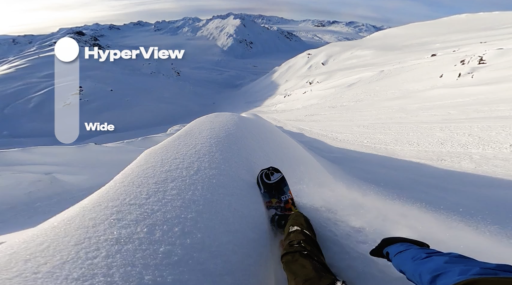 Snowboarder riding a spine of fresh powder using a GoPro Hero11 Black mounted to their head. The on screen graphic shows the HyperView Digital Lens selected in this tutorial video 