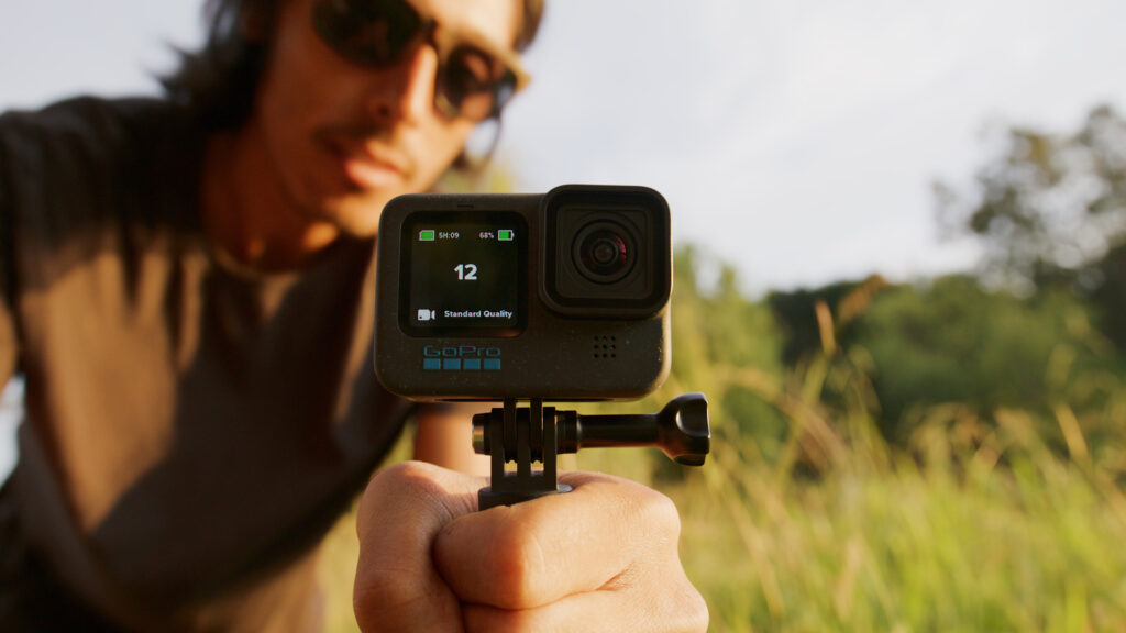 GoPro user holds the GoPro Hero 12 Black during sunset with the number 12 on the front screen of the camera