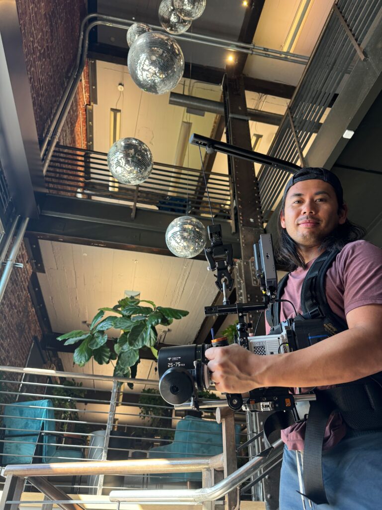 Jason Cayabyab holding the RED Komodo camera on an easy-rig Video Production Loft Orbital Disco Balls