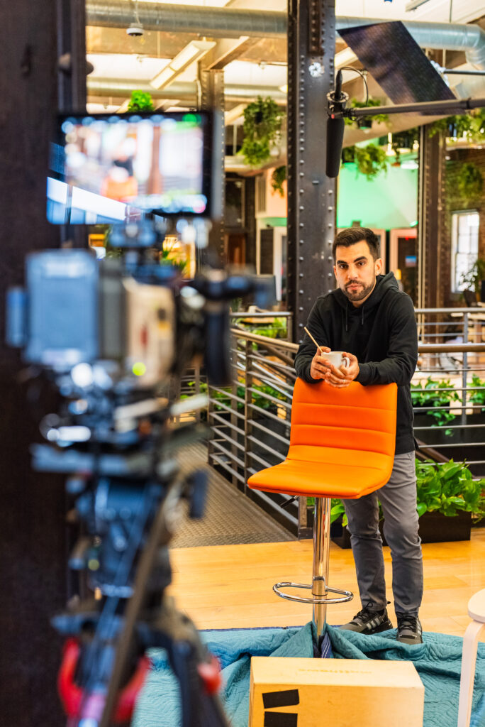 Thomas Grana Video Production Stand In Orange Chair Coffee Microphone interview Producer