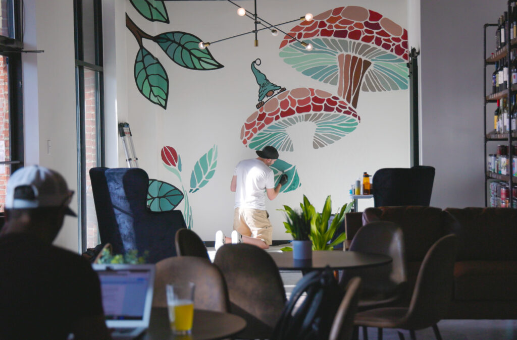 Ian Johnson AKA Endr Art paints a mural at WELD wine and beer while a remote worker has a beer