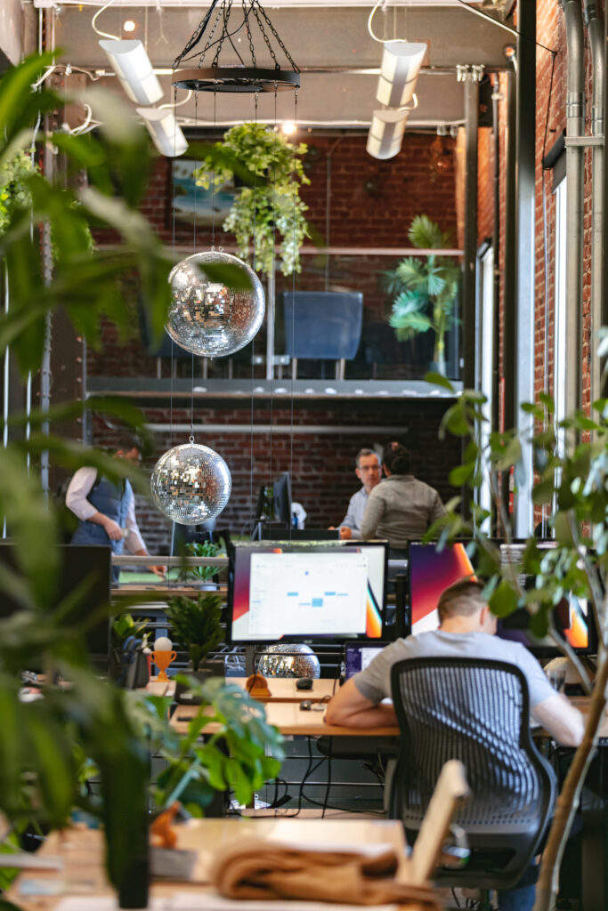 Loft Orbital San Francisco Office Disco balls hang while workers gather and meet type on computer